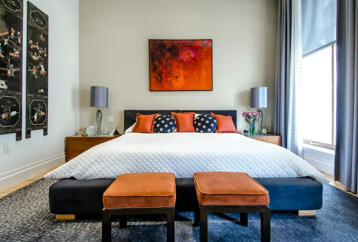 Bedroom with an orange bench and navy bedding